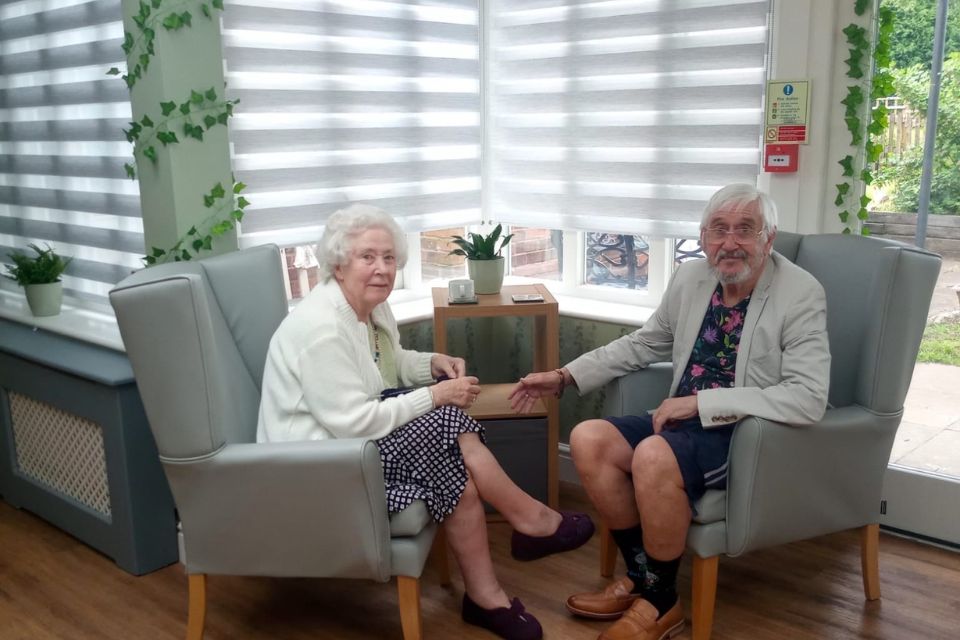Two elder people sitting and discussing