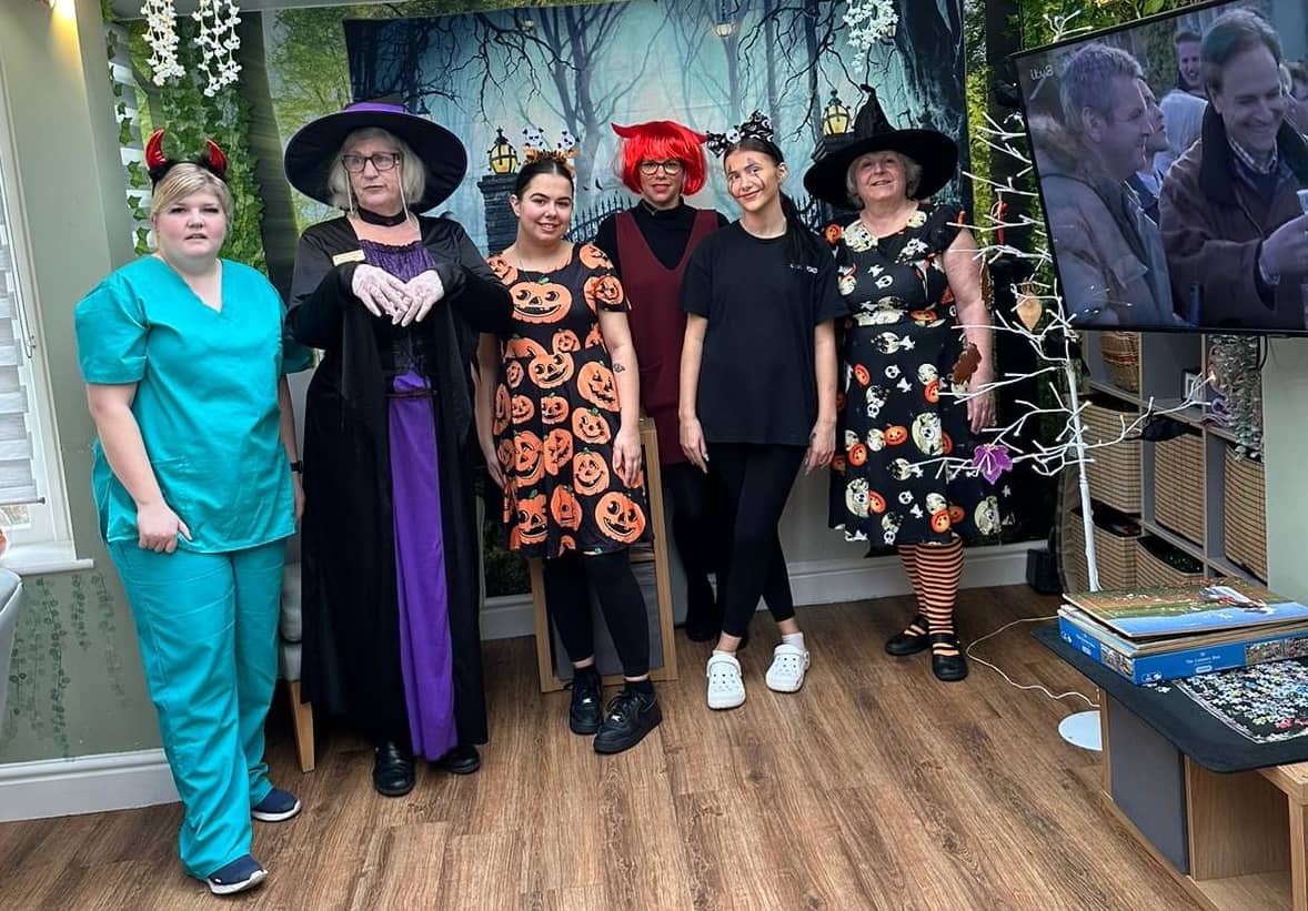 396960561_769385715201918_8724611203678465579_n Group in Halloween costumes posing indoors with decorations