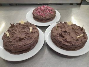 Three chocolate cakes, one with pink sprinkles, others with chocolate stars. Valentine's Day 2024 cakes.