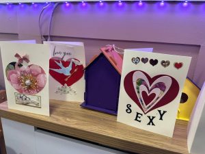 Valentine's Day cards and a birdhouse on a shelf. One card says "sexy.
