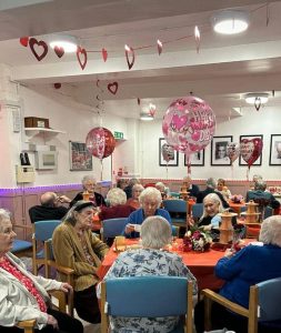 Seniors at a Valentine's Day 2024 party in a decorated room with balloons and heart streamers.